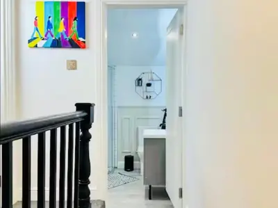 a hallway with a staircase with a painting on the wall at The Anfield Snug Terraced, 3 Bedroom Home with Ensuite & Free On-Street Parking in Liverpool