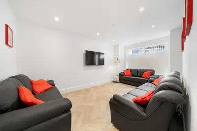 a living room with two black couches and orange pillows at Steven Gerrard Anfield House 6 bedroom house in Liverpool