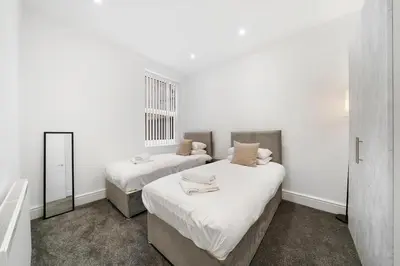 two beds in a room with white walls and a mirror at Steven Gerrard Anfield House 6 bedroom house in Liverpool