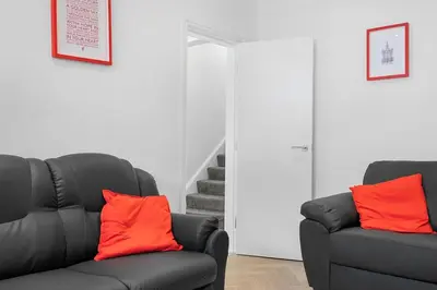 a living room with two black chairs and orange pillows at Steven Gerrard Anfield House 6 bedroom house in Liverpool