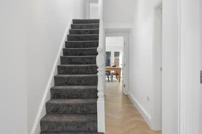 a staircase in a home with white walls at Steven Gerrard Anfield House 6 bedroom house in Liverpool