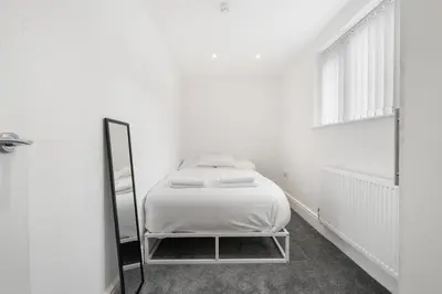 a white bedroom with a bed and a mirror at Steven Gerrard Anfield House 6 bedroom house in Liverpool