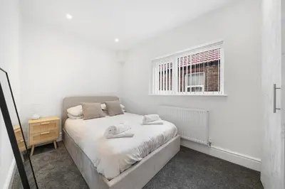 a white bedroom with a bed and a window at Steven Gerrard Anfield House 6 bedroom house in Liverpool