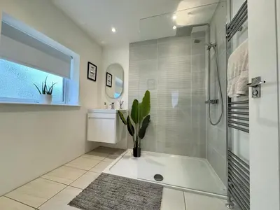 a white bathroom with a shower and a potted plant at Kendal By The Coast - Cosy home in great location in Blackpool
