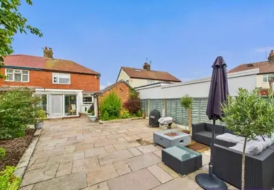 a garden with an umbrella and a patio at Kendal By The Coast - Cosy home in great location in Blackpool