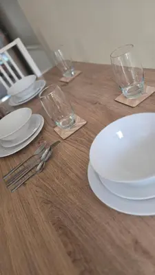 a wooden table with white plates and glasses on it at Two bedroom home in quite culdisac over looking hospital in Blackburn