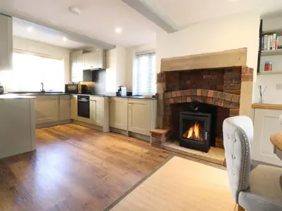 a kitchen with a brick fireplace in a living room at Gardener's Cottage in Lytham St Annes