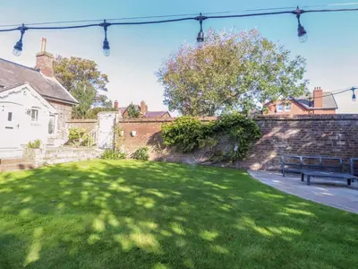 a park with a bench in front of a brick wall at Gardener's Cottage in Lytham St Annes