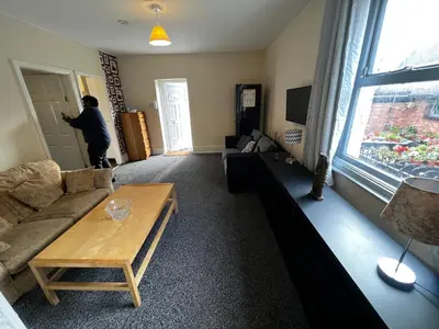 a man standing in a living room with a couch at Preston Central Flats in Preston