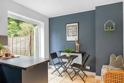 a kitchen with blue walls and a table and chairs at Cozy Haydock Home With Easy Transport Links in St Helens and Wi-Fi in Haydock