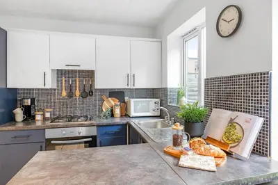 a kitchen with white cabinets and a counter top with bread at Cozy Haydock Home With Easy Transport Links in St Helens and Wi-Fi in Haydock