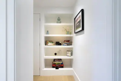 a corridor with white shelves in a white hallway at Fellbeck Holiday Home - Cartmel in the Lake District in Cartmel