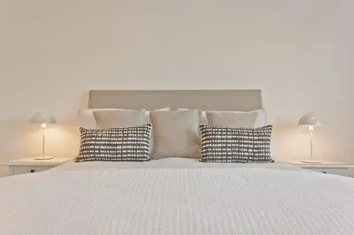 a white bed with pillows and two lamps on tables at Fellbeck Holiday Home - Cartmel in the Lake District in Cartmel
