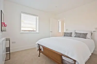 a white bedroom with a bed and a window at Fellbeck Holiday Home - Cartmel in the Lake District in Cartmel