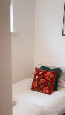 a red pillow sitting on top of a bed at Tastefully decorated 3 bed home in Formby