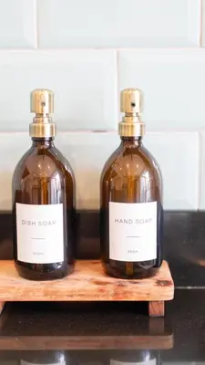 two bottles of hand soap sitting on a wooden shelf at Tastefully decorated 3 bed home in Formby