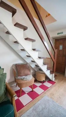 a living room with a staircase with a chair and a rug at Tastefully decorated 3 bed home in Formby