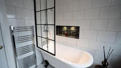 a white bath tub in a white tiled bathroom at Tastefully decorated 3 bed home in Formby