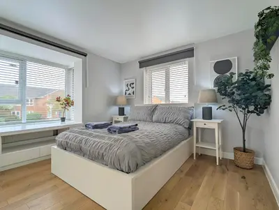 a white bedroom with a bed and two windows at Spacious 5BR Home Near Central Liverpool Parking in Liverpool