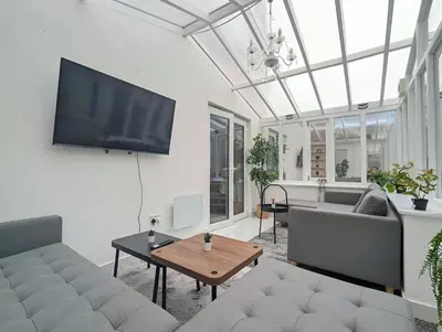 a living room with a couch and a flat screen tv at Spacious 5BR Home Near Central Liverpool Parking in Liverpool
