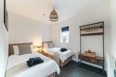 a bedroom with two beds and a mirror at Cosy 2 bed flat in Merseyside in Southport