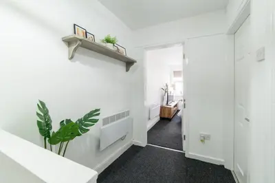 a hallway with white walls and a plant on the wall at Cosy 2 bed flat in Merseyside in Southport