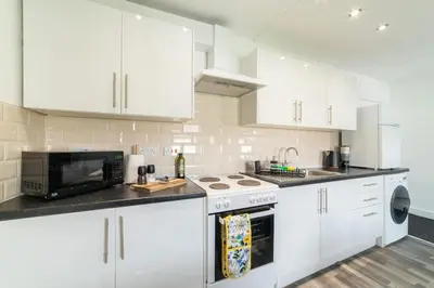 a kitchen with white cabinets and a microwave at Cosy 2 bed flat in Merseyside in Southport