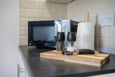a kitchen counter with a microwave and a cutting board at Cosy 2 bed flat in Merseyside in Southport