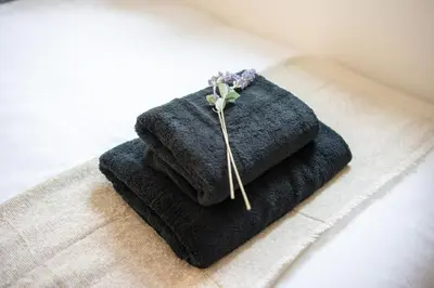 a pile of towels on a towel with a flower on it at Cosy 2 bed flat in Merseyside in Southport