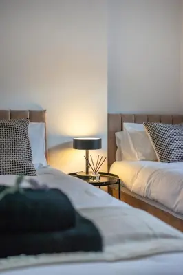 a bedroom with two beds and a lamp on a table at Cosy 2 bed flat in Merseyside in Southport