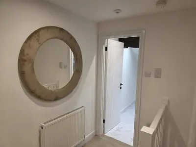 a round mirror on the wall of a hallway at Liverpool Penthouse - Sleeps 8 - City Centre in Liverpool