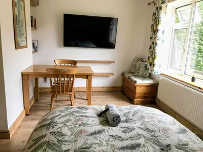 a room with a table and a tv on the wall at Peaceful Large Double Room l 55inch TV l Garden View in Egerton