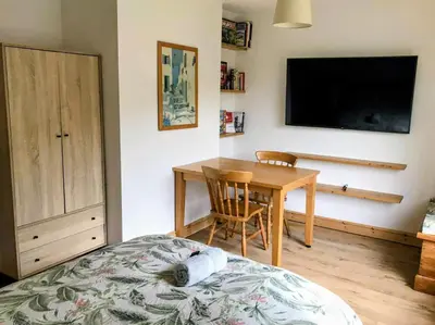a bedroom with a bed and a table and a television at Peaceful Large Double Room l 55inch TV l Garden View in Egerton