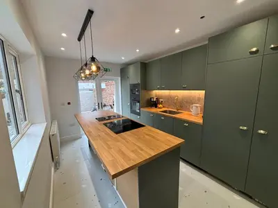 a kitchen with green cabinets and a wooden counter top at Bedford Guesthouse in Liverpool