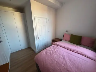 a small bedroom with a pink bed and a door at Bedford Guesthouse in Liverpool