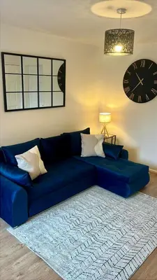a blue couch in a living room with a clock on the wall at Modern House on the Mersey in Wallasey
