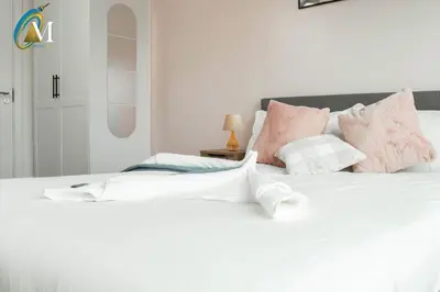 a bedroom with a white bed with pink pillows at Oriel Nubian walls in Liverpool