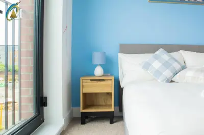 a bedroom with a bed and a nightstand next to a window at Oriel Nubian walls in Liverpool
