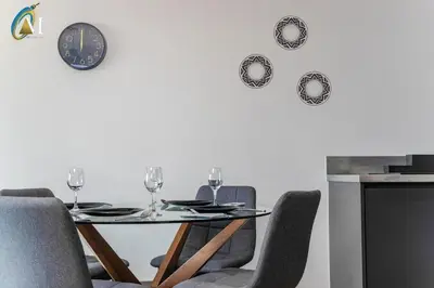 a dining room table with chairs and a clock on the wall at Oriel Nubian walls in Liverpool