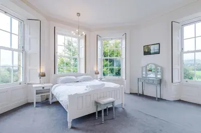 a white bedroom with a white bed and windows at Escowbeck House - Staycation - HotTub - Sleeps 8 in Lancaster