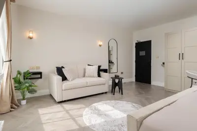 a white living room with a couch and a mirror at Bold St ApartHotel Book Individually or Book 8! in Liverpool