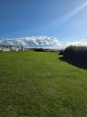 a large grassy field with houses in the background at Poppy Lodge LE 17 Ocean's Edge Park in Morecambe