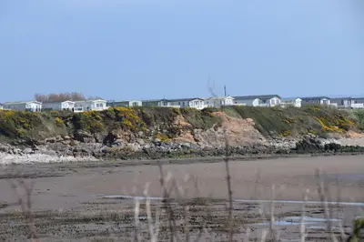 a beach with houses on top of a hill at Poppy Lodge LE 17 Ocean's Edge Park in Morecambe