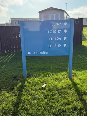 a blue sign in the middle of a field at Poppy Lodge LE 17 Ocean's Edge Park in Morecambe