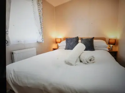 a bedroom with a white bed with towels on it at Poppy Lodge LE 17 Ocean's Edge Park in Morecambe