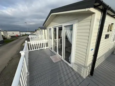 a small white house with a large window on a deck at Poppy Lodge LE 17 Ocean's Edge Park in Morecambe