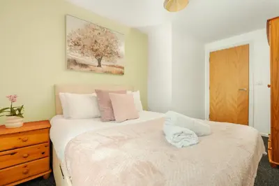 a bedroom with a white bed with a wooden dresser at Premium 10-Room Contractor Accommodation Central Location in Liverpool