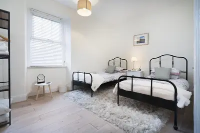 two beds in a white room with a rug at Three Bridges - 1-Mile from Ulverston Town Centre in Ulverston