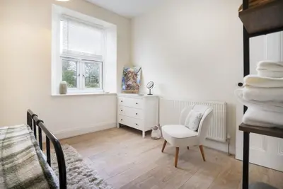 a bedroom with a chair and a dresser and a window at Three Bridges - 1-Mile from Ulverston Town Centre in Ulverston