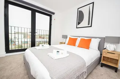 a bedroom with a bed with orange pillows and a window at Fabulous Modern 2 Bedroom Apartment in Liverpool in Liverpool